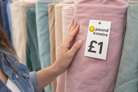 Female sewing with pound fabrics on a worktable, face hidden, affordable fabric shopping inspiration