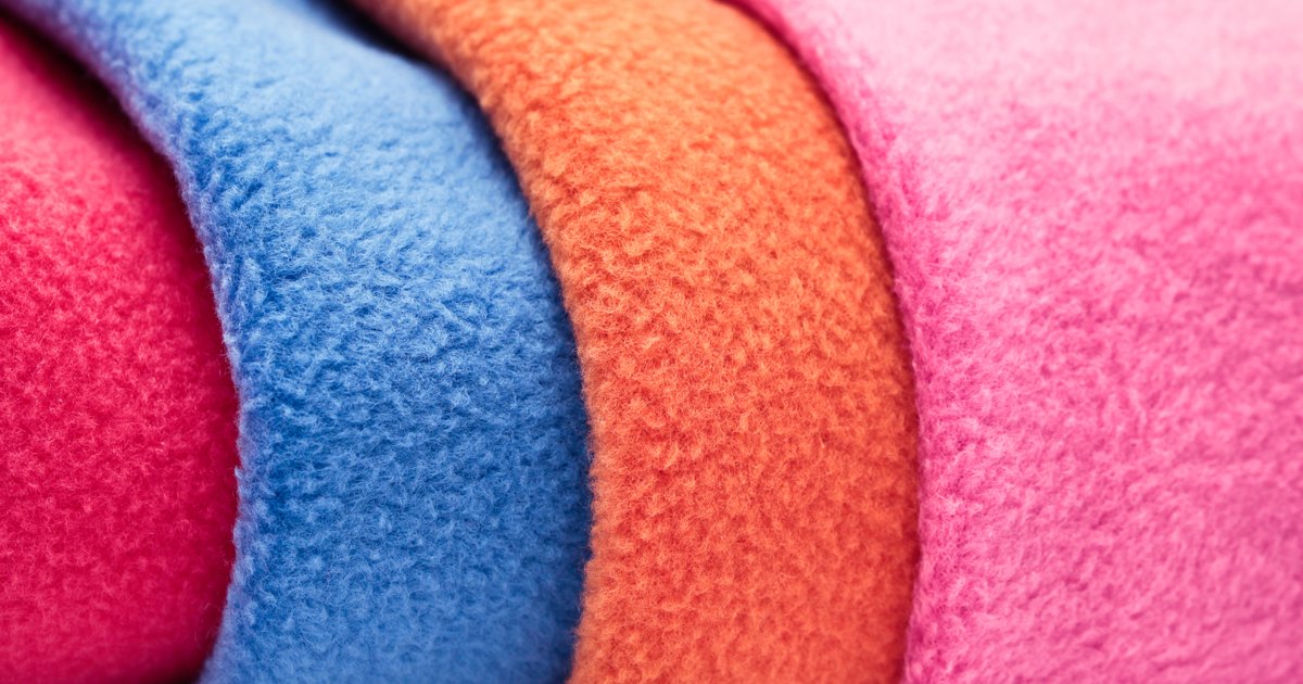 Close-up of folded polar fleece fabric in red, blue, orange and pink, showing the brushed pile