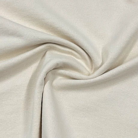 Plain fabric folded on a wooden table in natural light, showing colour depth and fabric texture.