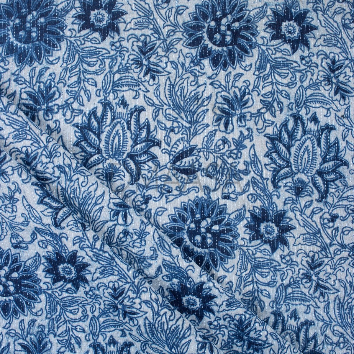 Printed fabric folded neatly on a wooden table in natural light, showing pattern detail and fabric texture.