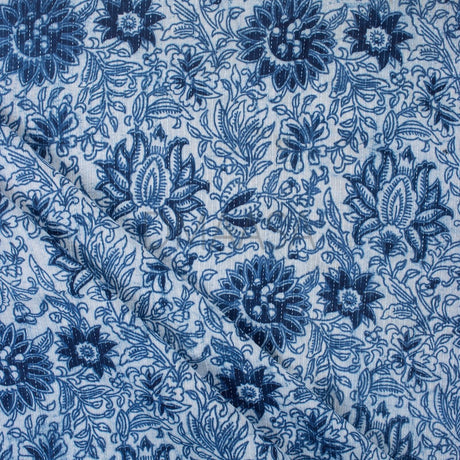 Printed fabric folded neatly on a wooden table in natural light, showing pattern detail and fabric texture.