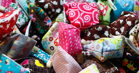 Pile of handmade zip pouches in colourful cotton prints, the kind of small gift that sells at craft fairs