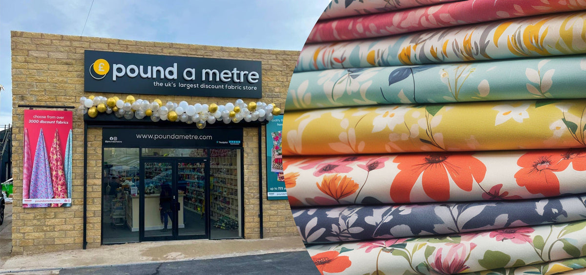 Fabric store exterior with 'Pound a Metre' sign and colorful fabric stacks.